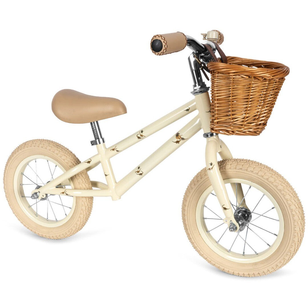Konges Sløjd beige loopfiets met dinosaurusfiguren en rotan mandje.