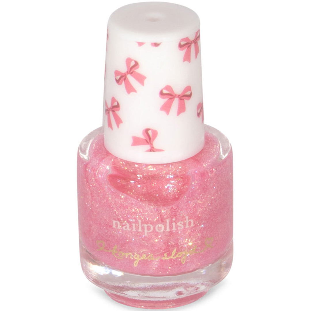 Detail van een Konges Sløjd flesje roze glitter nagellak met een dop versierd met strikjes.
