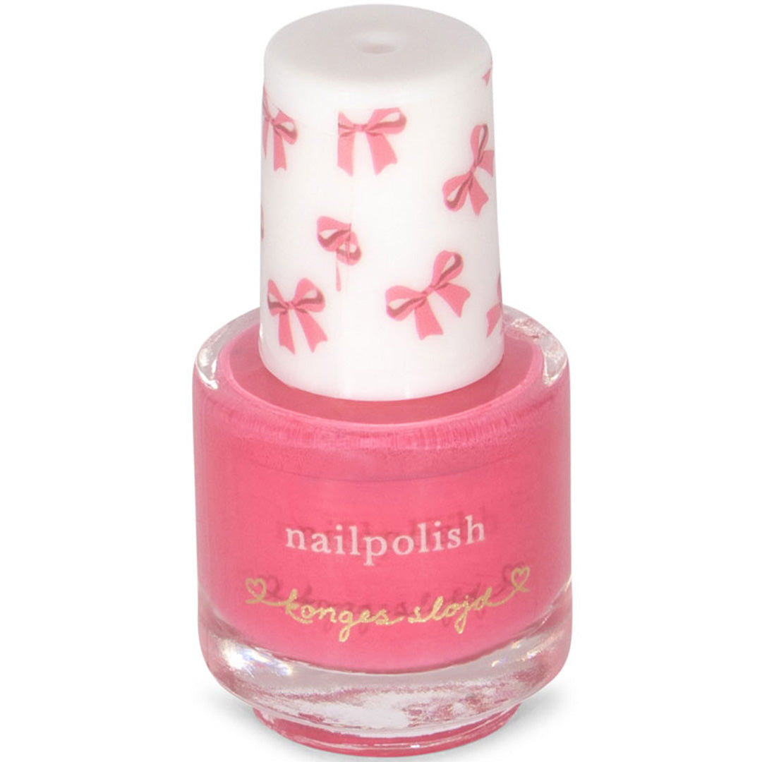 Detail van een Konges Sløjd flesje effen roze nagellak met een dop versierd met strikjes.