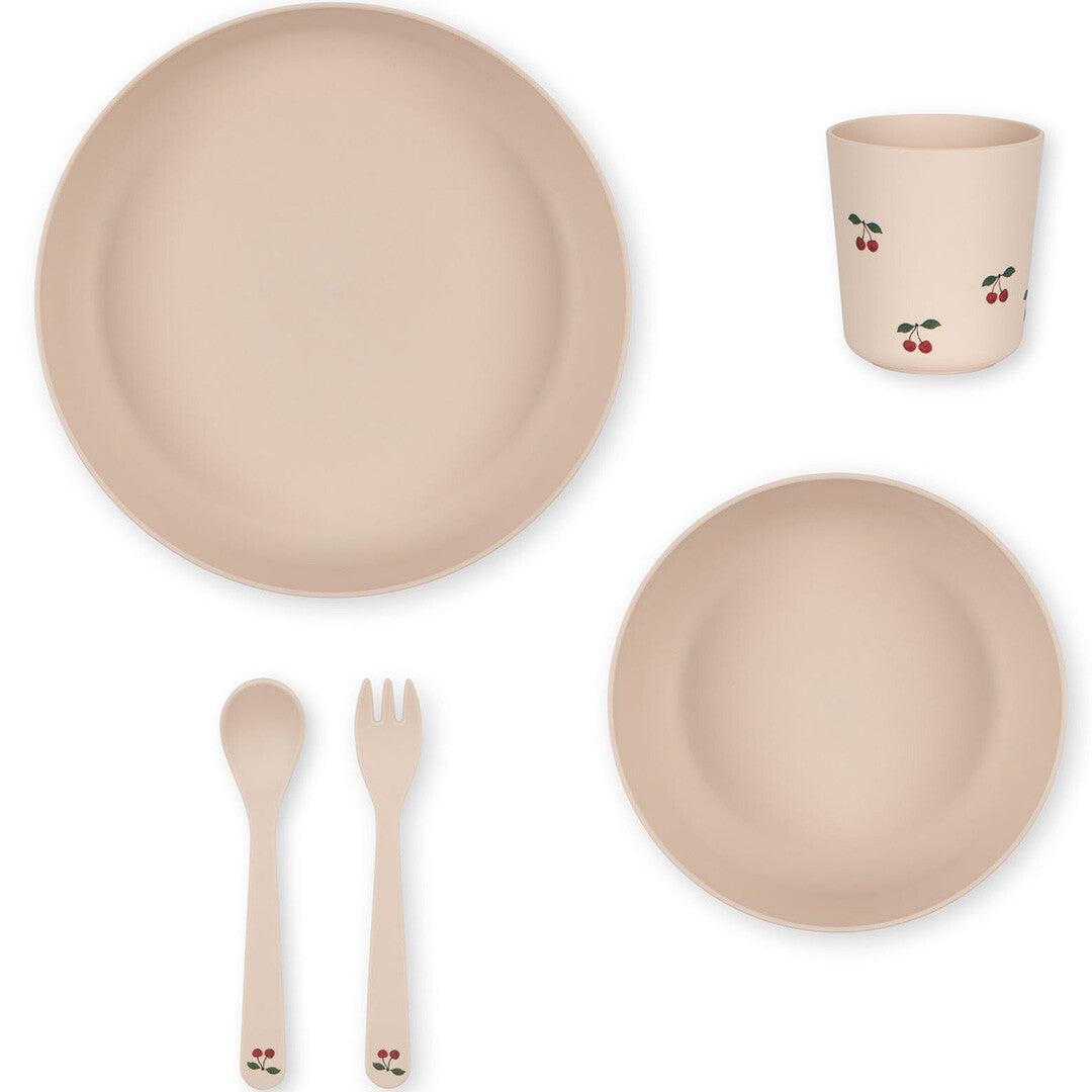 Bovenaanzicht van het Konges Sløjd beige kinderservies met kersjesprint, met een bord, kom, beker, vork en lepel.