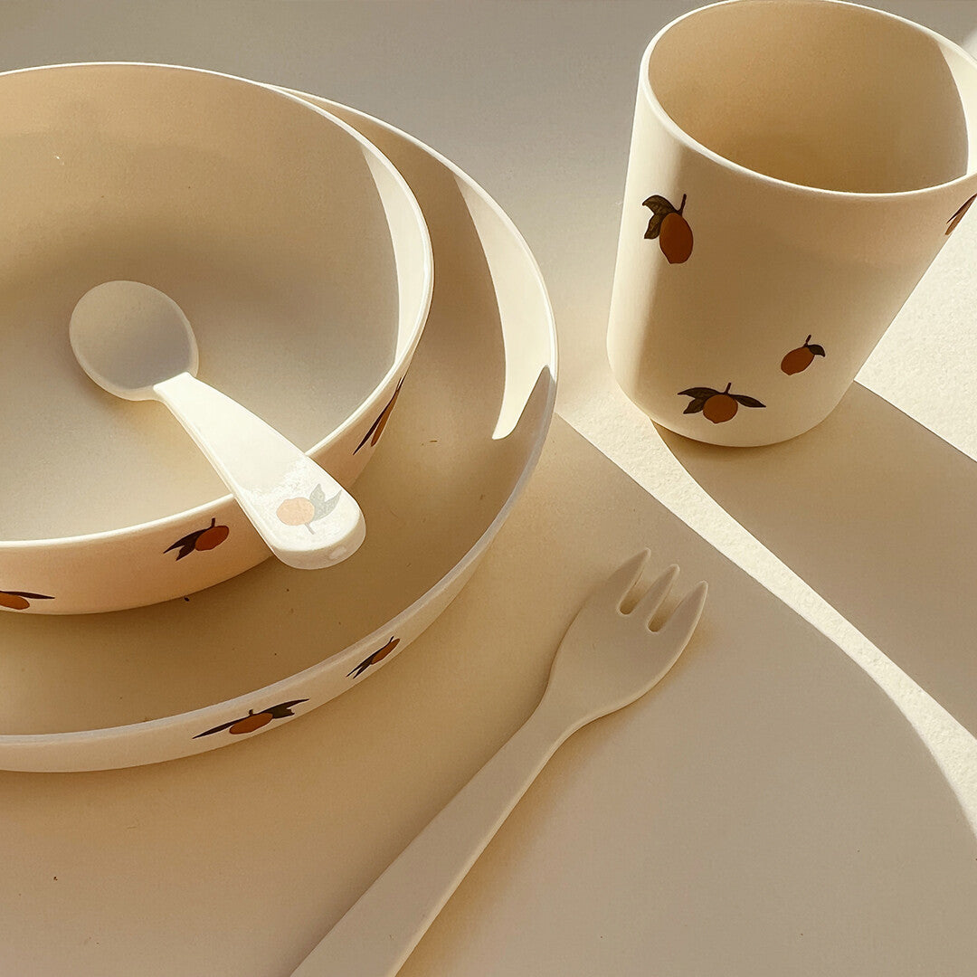 Detail van het Konges Sløjd beige kinderservies met citroenprint, met een kom, bord, beker en vork.