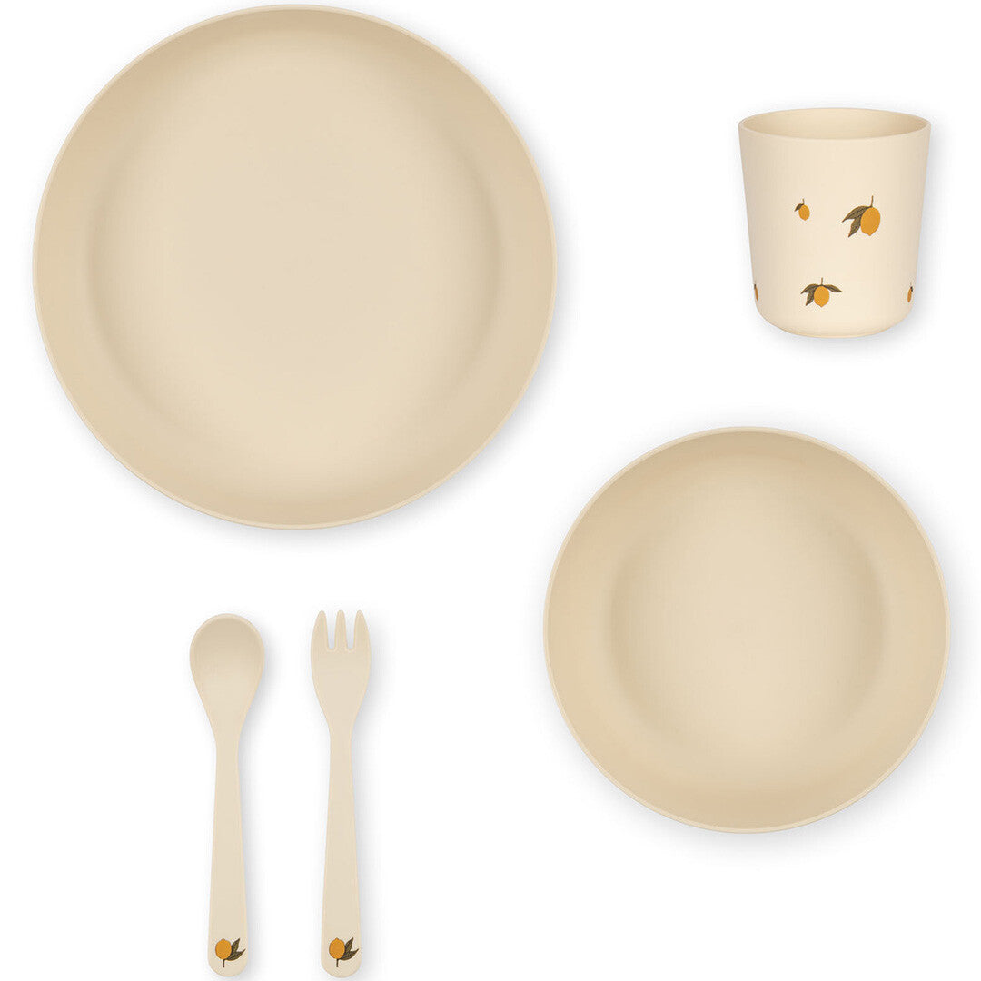 Bovenaanzicht van het Konges Sløjd beige kinderservies met citroenprint, met twee borden, een beker, lepel en vork.