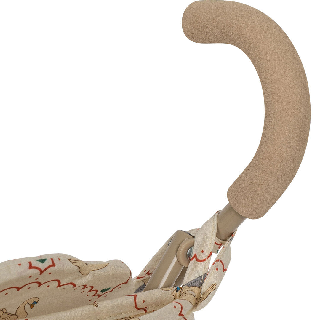 Detail van de beige handgreep van de poppenbuggy met zwanenpatroon.