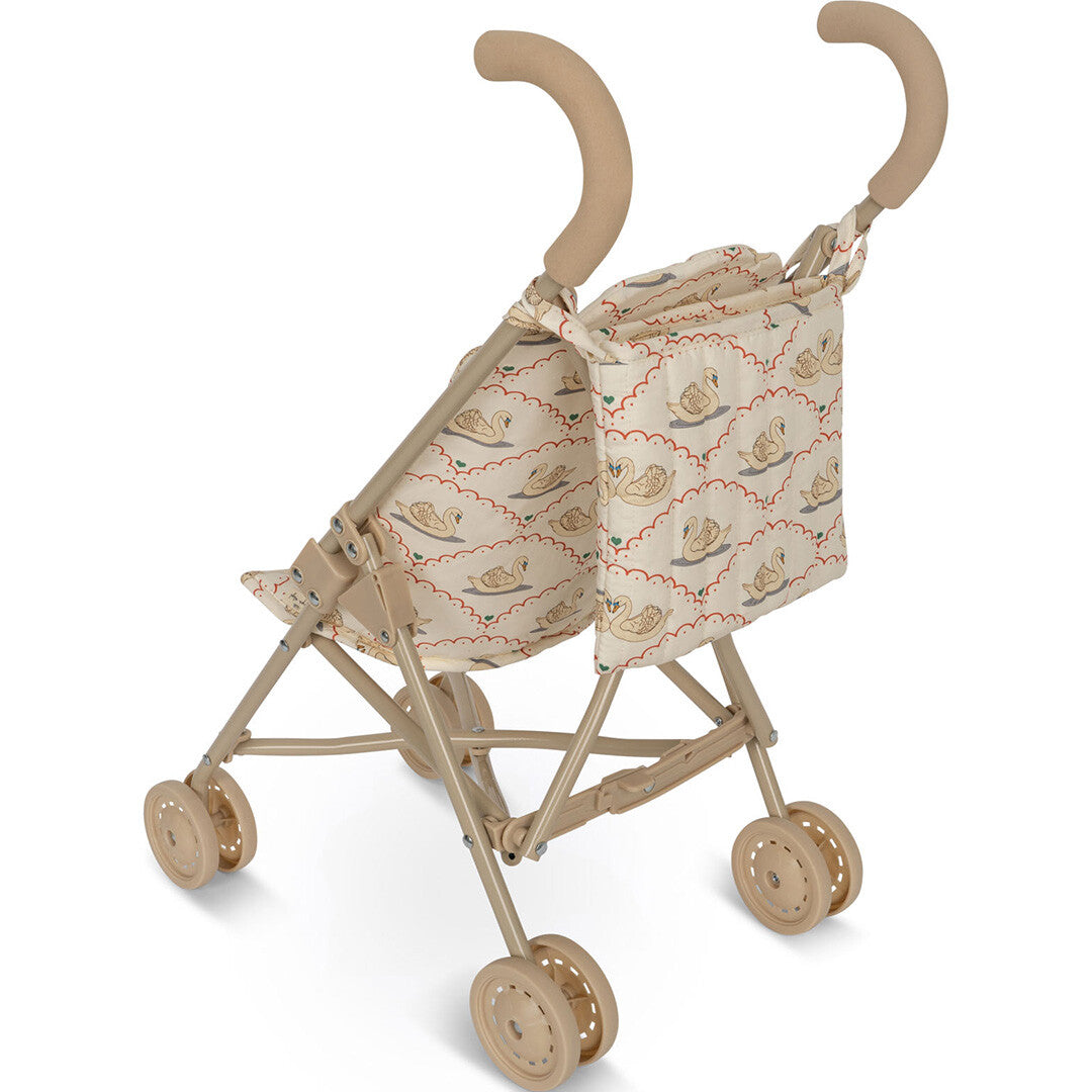 Konges Sløjd poppenbuggy in beige met zwanenpatroon, schuin van achteren gefotografeerd.