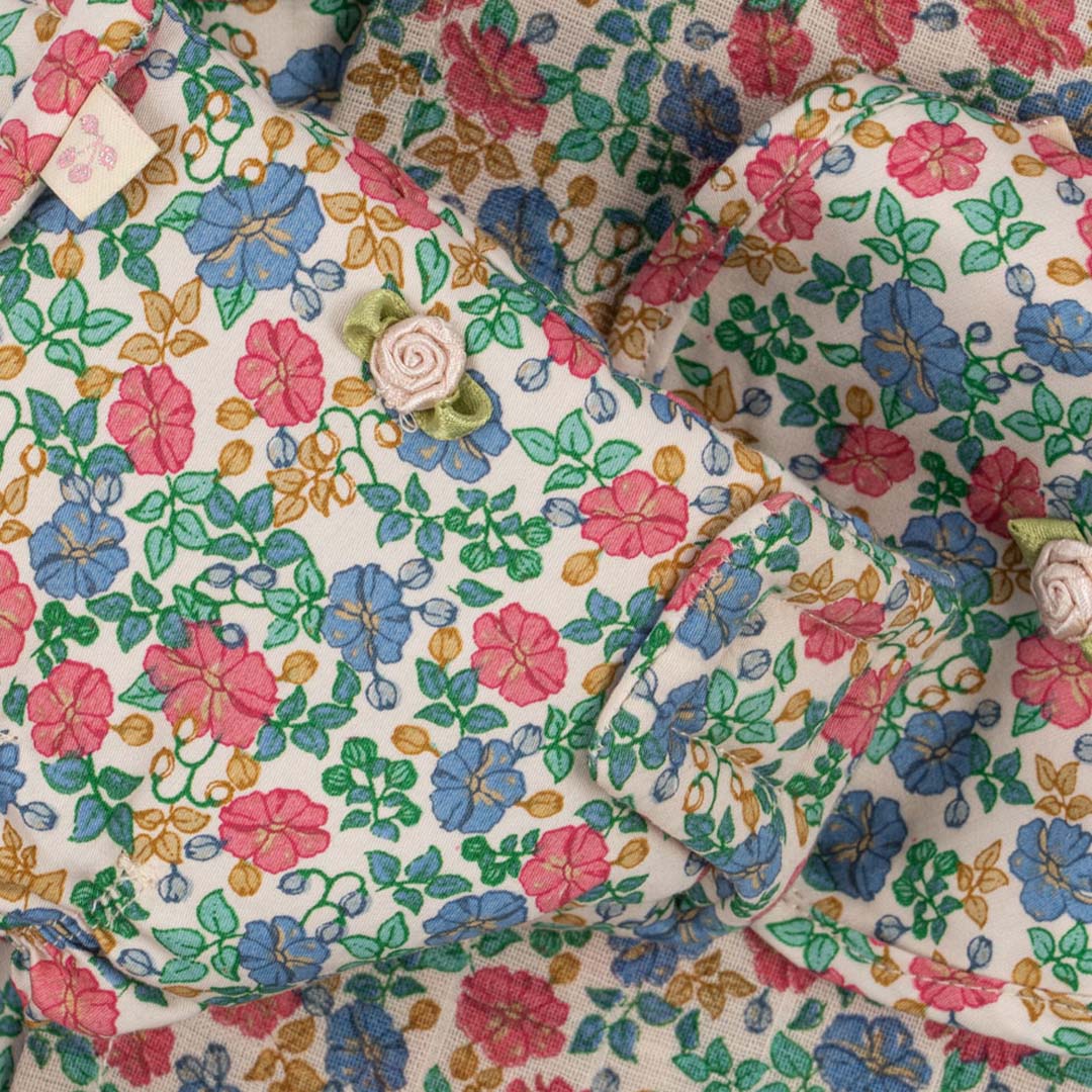 Detail van de Konges Sløjd poppenverzorgingsset met gebloemd patroon en roze roosjes.