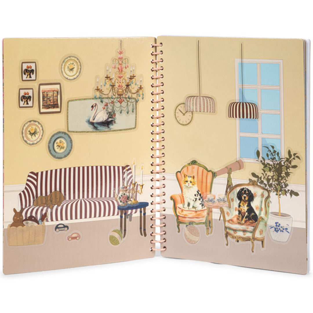 Open Konges Sløjd stickerboek met een kamerinterieur en geplaatste dierenstickers.