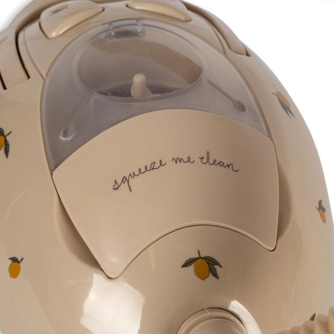 Detail van de beige speelgoed stofzuiger met citroenpatroon en de tekst 'squeeze me clean'.