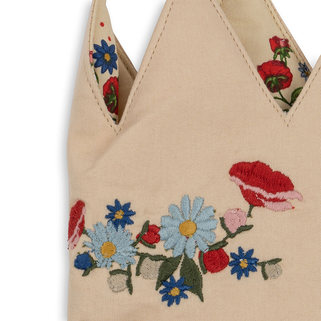 Detail van de geborduurde blauwe en rode bloemen op de beige verjaardagskroon.