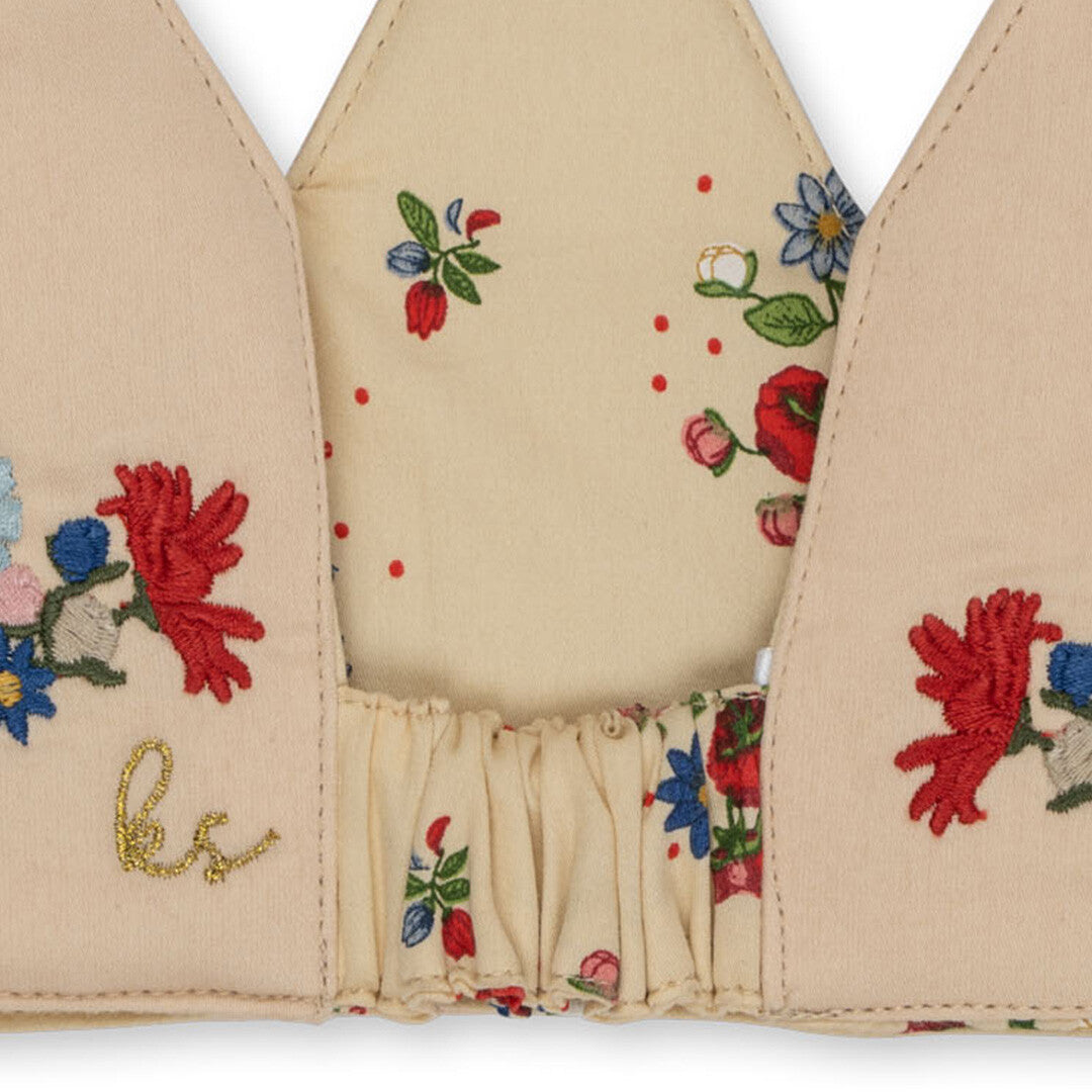 Detail van de elastische achterkant van de beige verjaardagskroon met geborduurde bloemen en het Konges Sløjd logo.