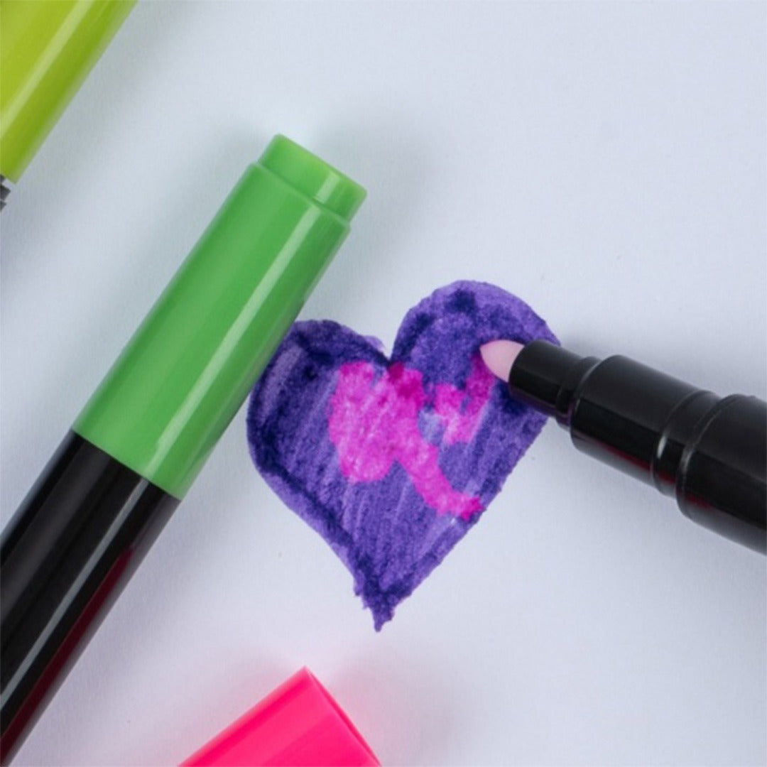 Een zwarte viltstift tekent een roze figuur in een paars hart op wit papier, met een groene stift ernaast.