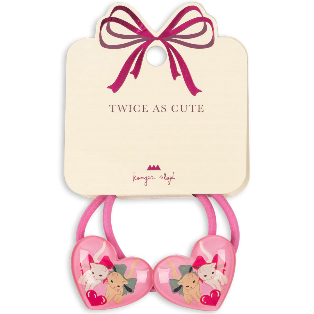 Verpakking van twee roze Konges Sløjd haarelastieken voor kinderen met hartvormige bedels van kittens.