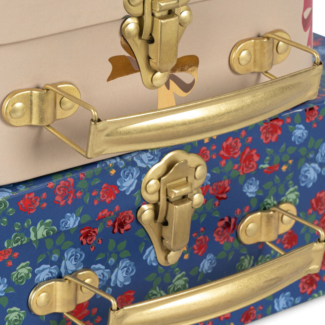 Detail van de gouden sluitingen en handvatten van de Konges Sløjd kinderkoffers met bloemen- en strikjespatroon.