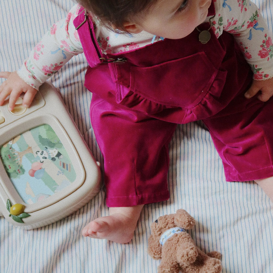 Een baby speelt op een gestreepte deken met de Konges Sløjd muzikale tv.