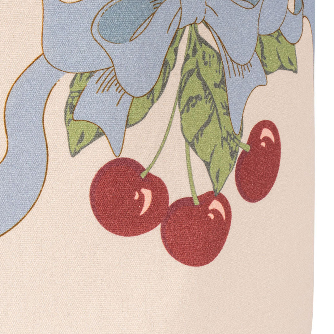 Detail van het kersen- en strikpatroon op een beige katoenen opbergmand.