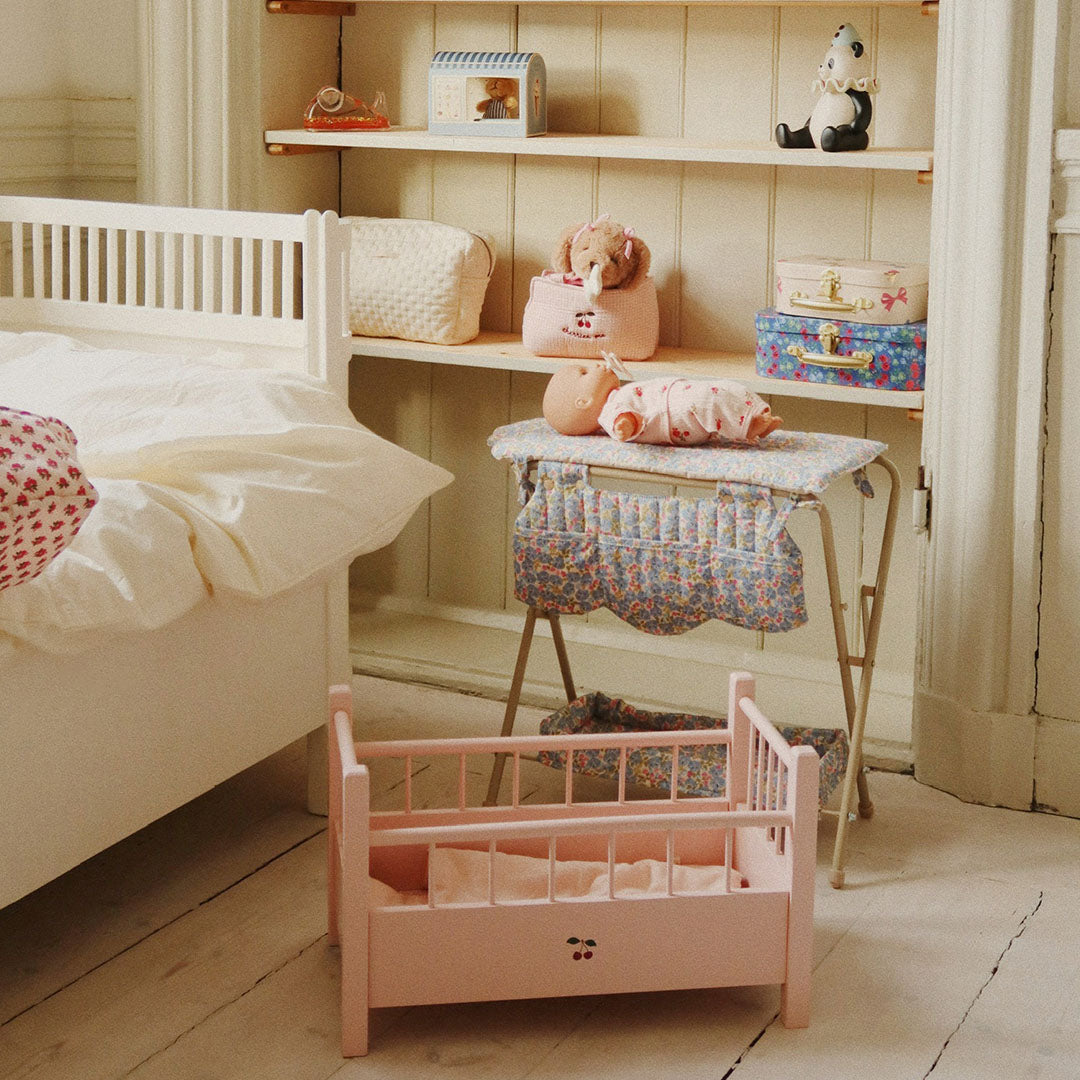 De Konges Sløjd poppenverschoontafel met gebloemd patroon staat in een kinderkamer naast een poppenbedje.