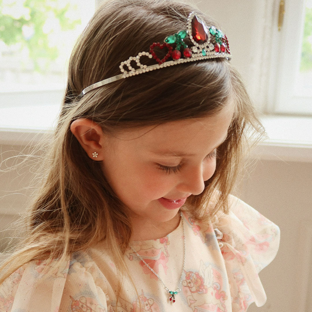 Een meisje draagt de Konges Sløjd prinsessenkroon en ketting met kersenmotief.