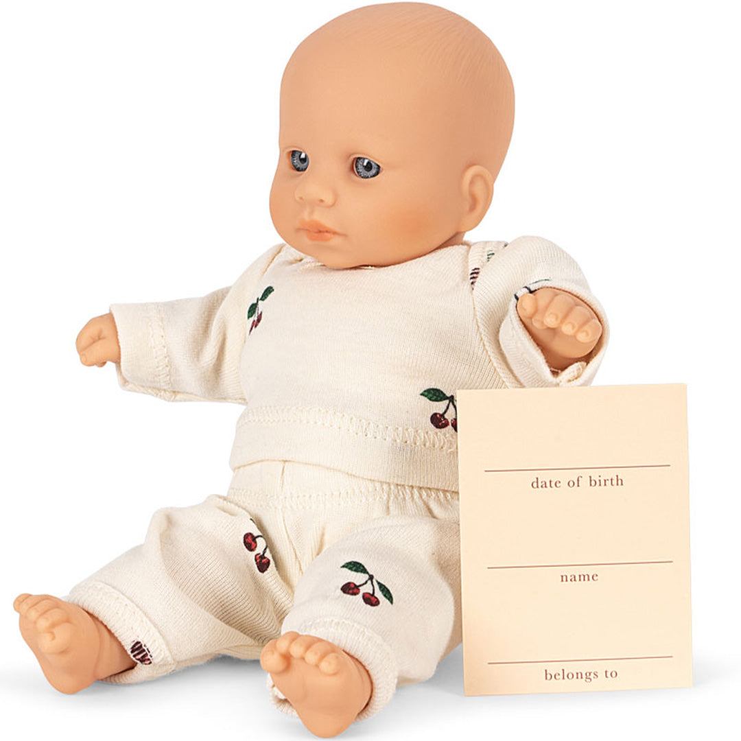 Konges Sløjd babypop zittend naast een invulkaartje voor geboortedatum en naam.