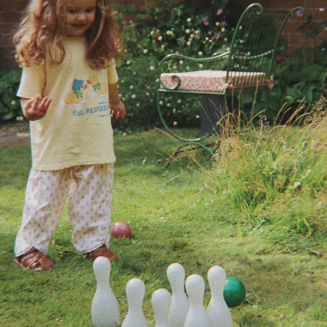 Een peuter speelt buiten in een tuin met het glitter kegelspel.