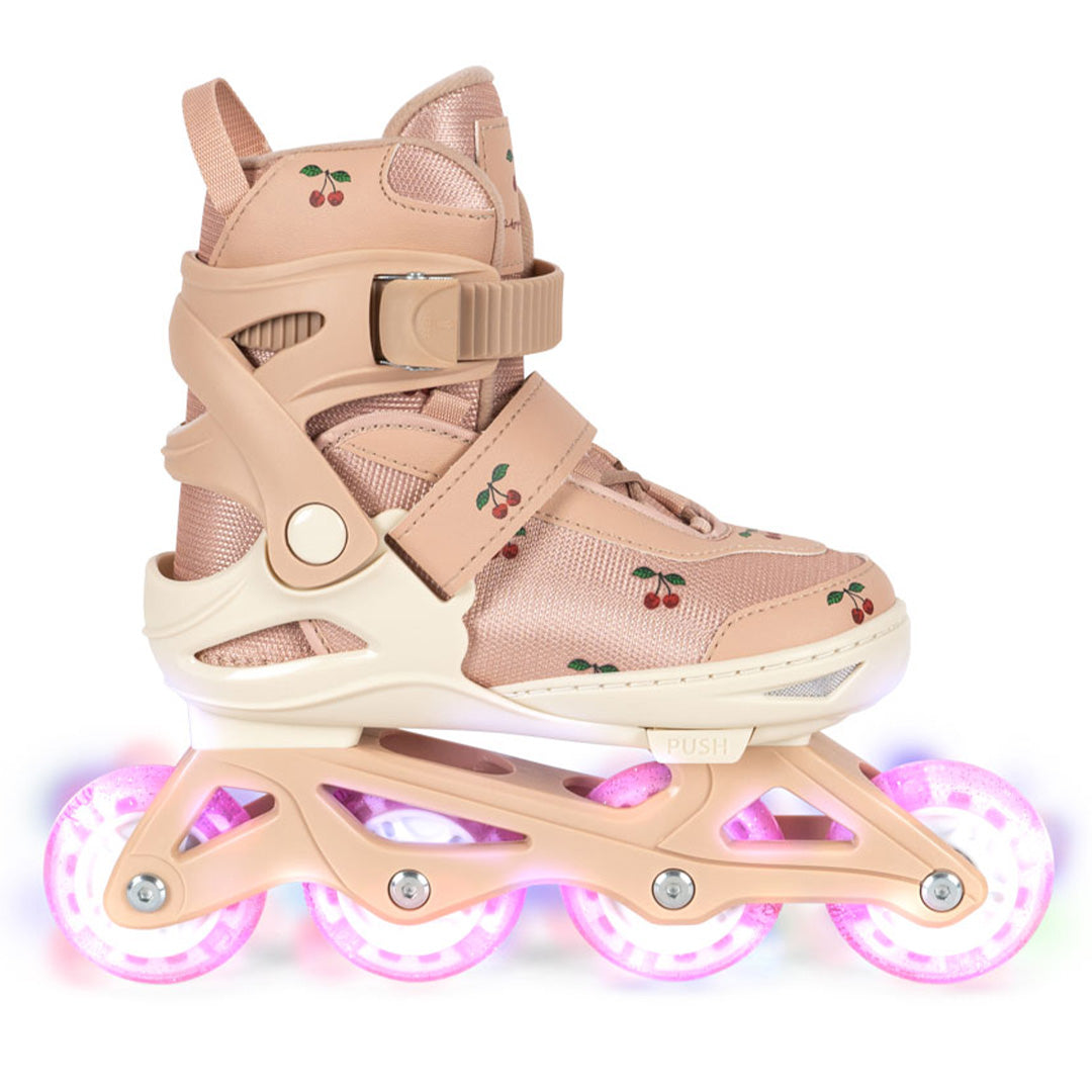 Een Konges Sløjd kinderskeeler in cherry blush met kersenpatroon en oplichtende roze wielen, van de zijkant gefotografeerd.
