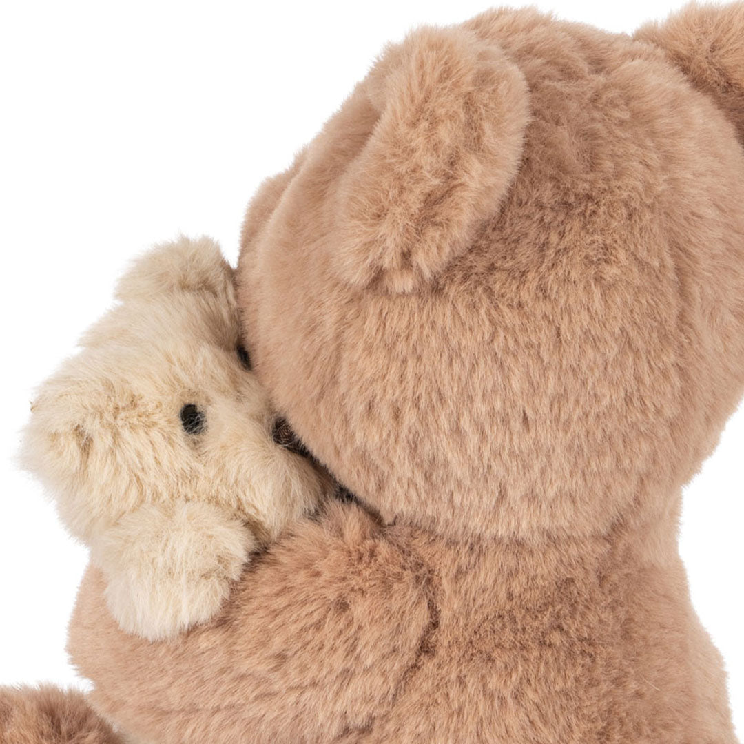 Detail van de Konges Sløjd pluchen knuffelbeer die een kleinere, lichtere knuffelbeer vasthoudt, schuin van achteren gezien.