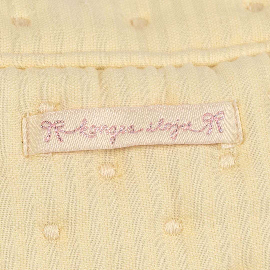 Detail van de gele gequilte stof van de toilettas met het roze Konges Sløjd logo.