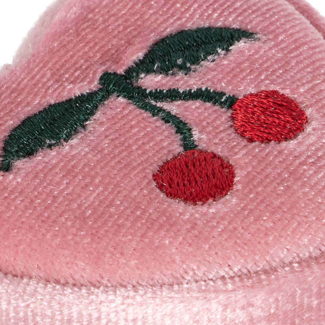 Close-up van het geborduurde kersenpatroon op het roze fluwelen doosje.