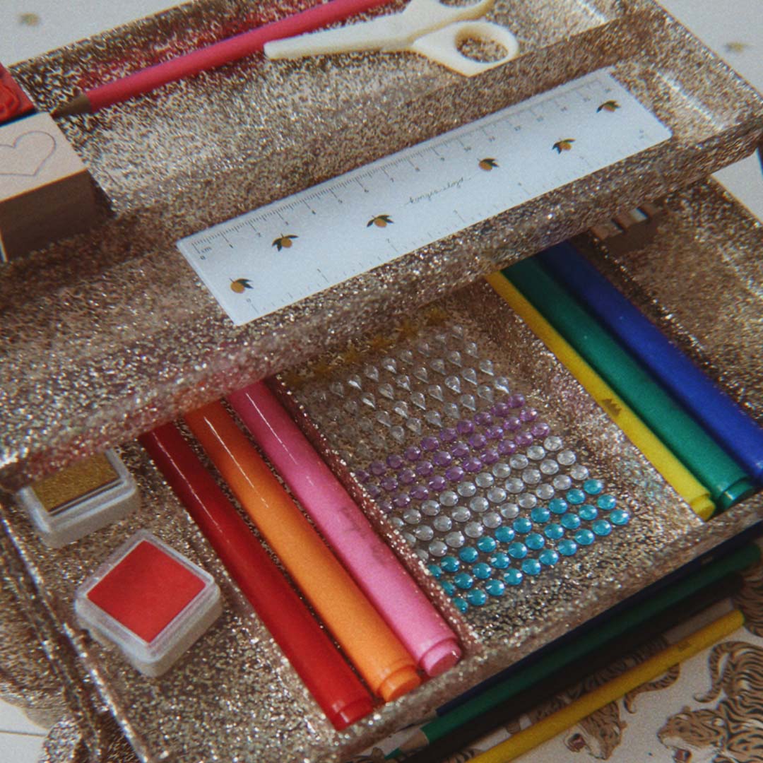 Detail van de Konges Sløjd gouden glitter knutselset met stiften, potloden, plaksteentjes en een liniaal.