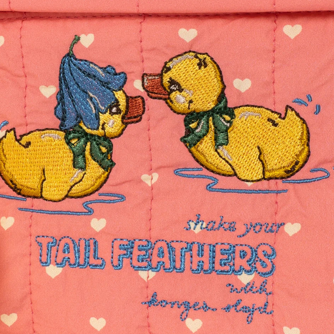 Detail van het geborduurde eendenontwerp en de tekst "shake your TAIL FEATHERS" op de roze peuterrugzak.