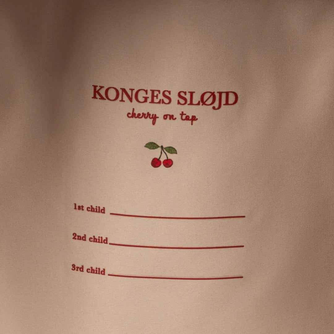 Detail van het Konges Sløjd label aan de binnenkant van de rugzak met de tekst 'cherry on top' en invulregels voor kinderen.