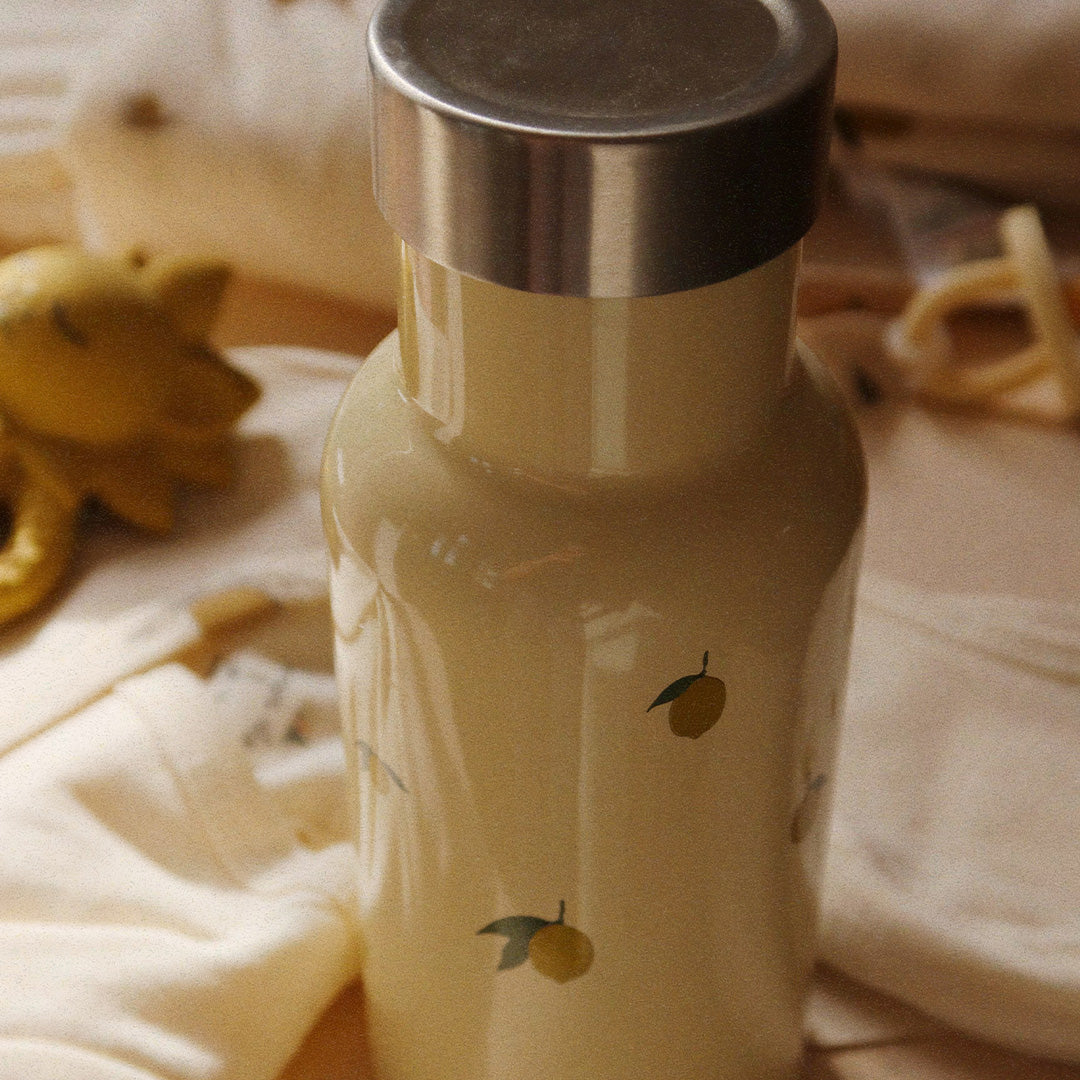 Detail van een Konges Sløjd beige thermosfles met citroenpatroon en zilveren dop op een lichte ondergrond.