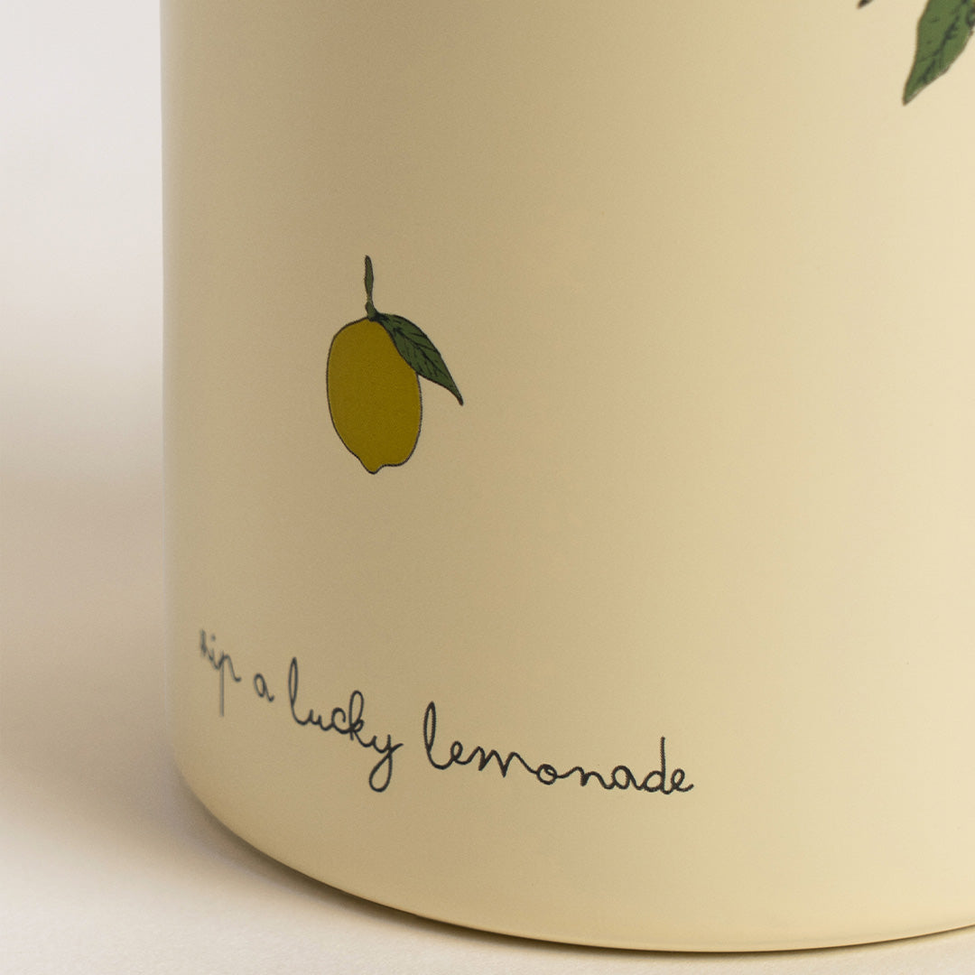 Detail van de Konges Sløjd beige thermosfles met een citroenillustratie en de tekst 'sip a lucky lemonade'.