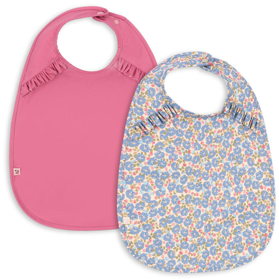 Konges Sløjd set van twee baby slabbetjes, één effen roze en één met blauw bloemenpatroon.