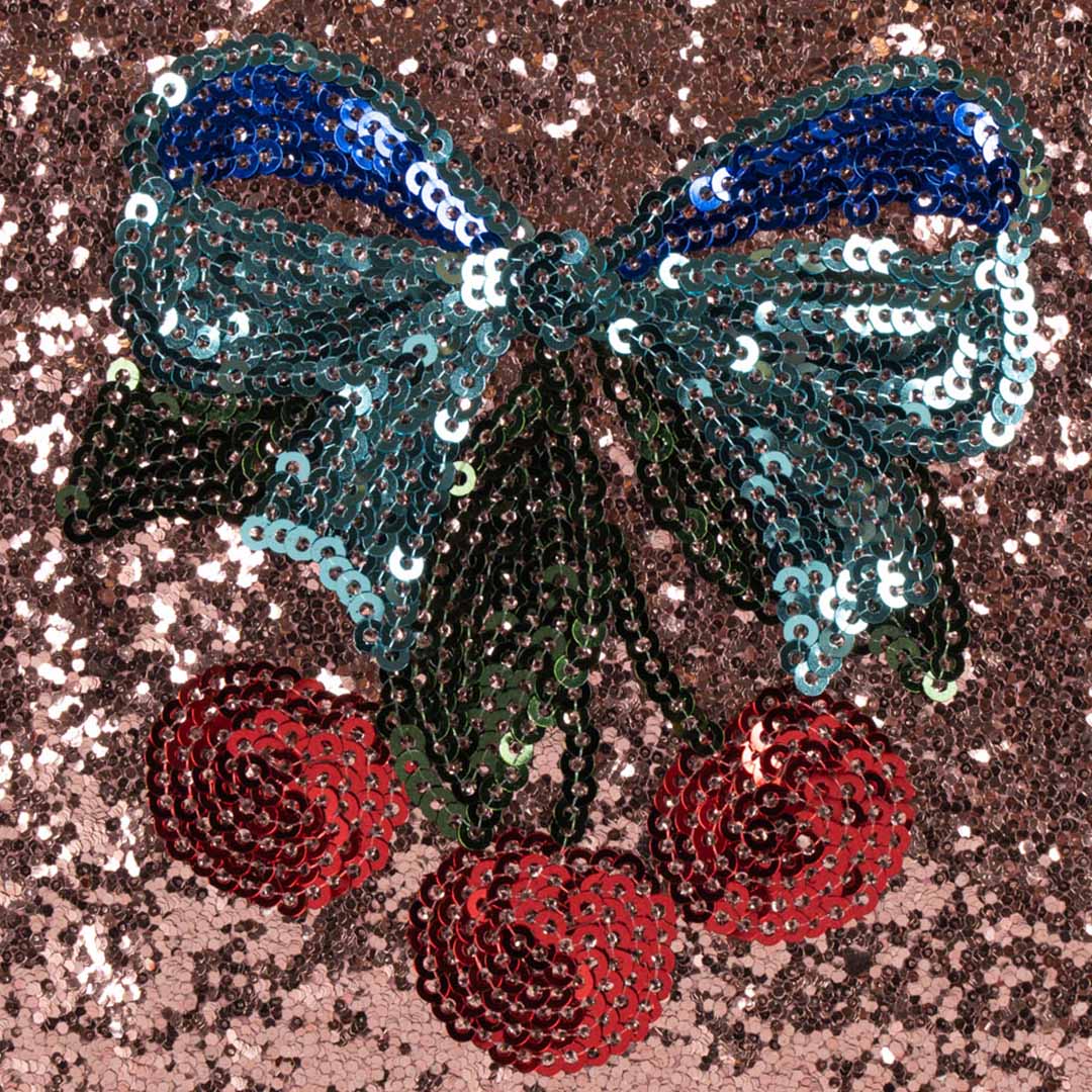 Detail van de pailletten kersen en blauwe strik op de glitter roze speelgoed toilettas.