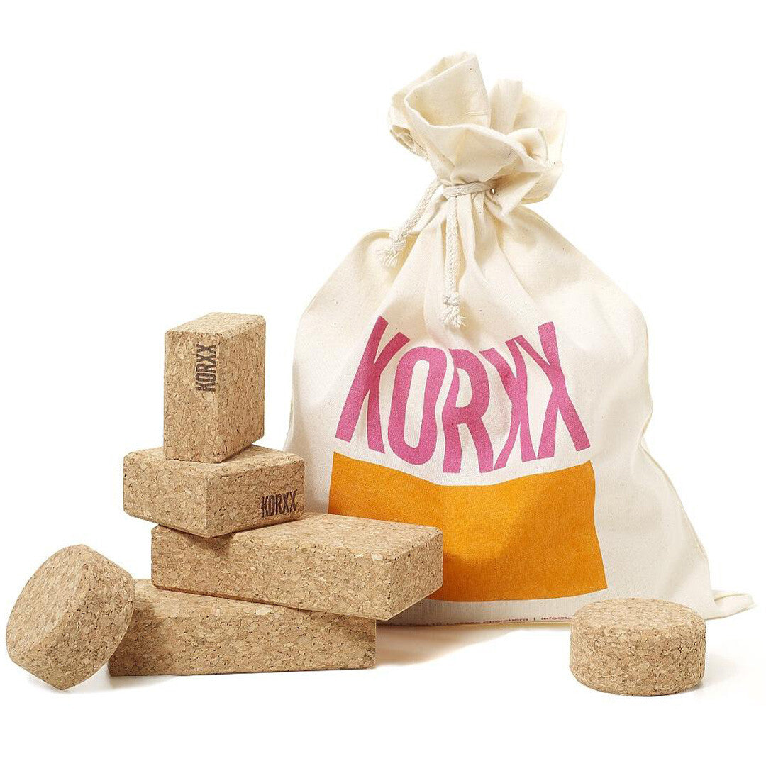 KORXX kurk baby bouwblokken in verschillende vormen naast een katoenen opbergzak.