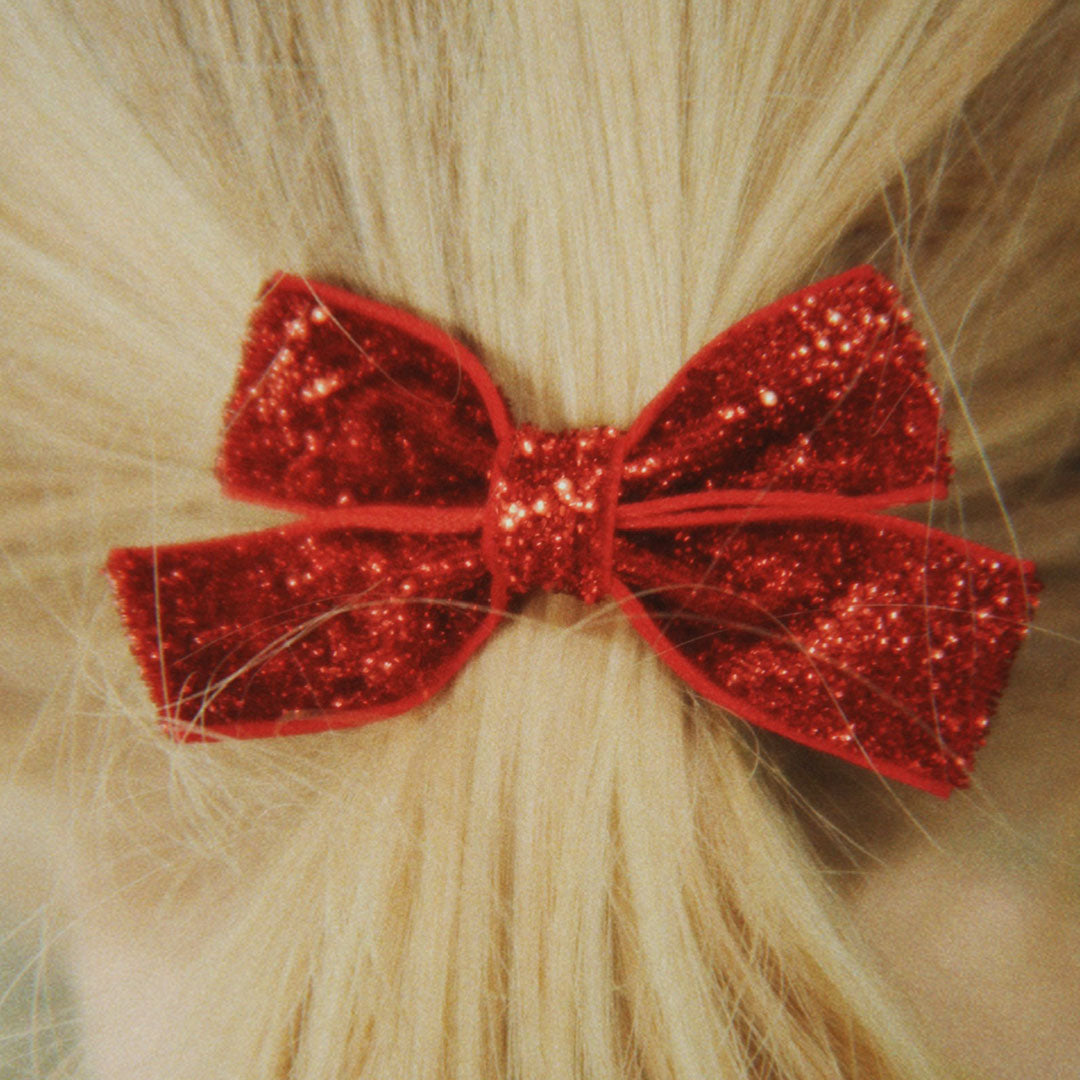 Een rode glitter haarclip in een blonde paardenstaart van een kind.
