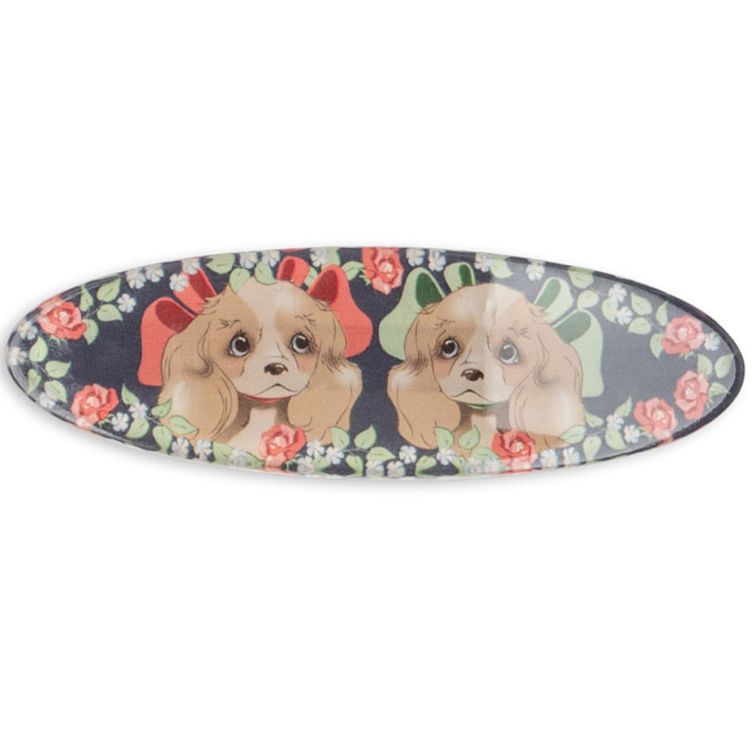 Konges Sløjd haarclip met twee puppy's met strikken en een gebloemd patroon op een marineblauwe achtergrond.