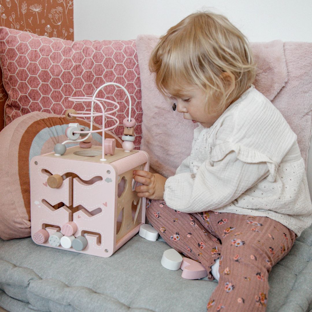 Een kind speelt met de label label roze houten activiteitenkubus.
