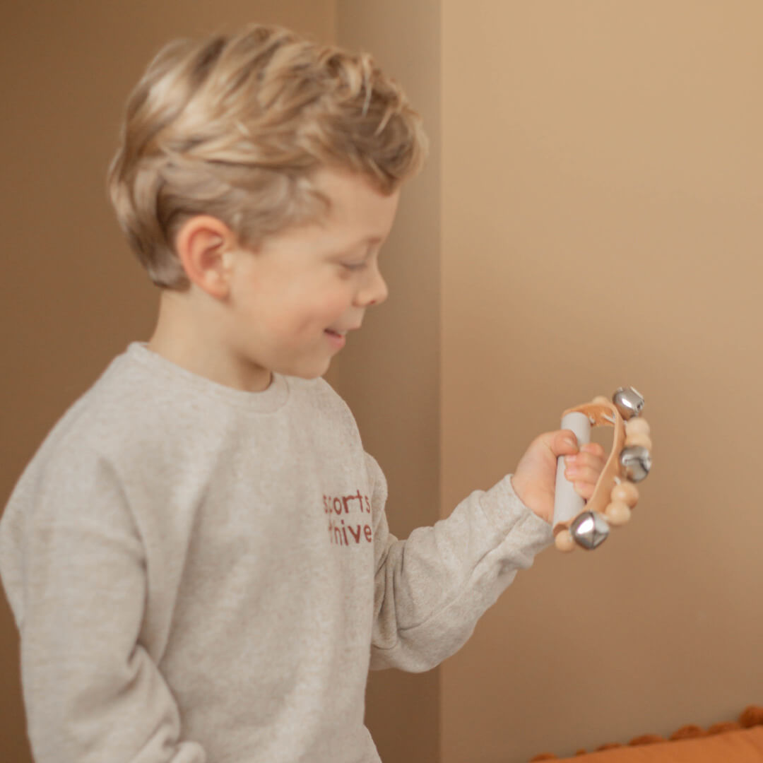 Een lachende jongen houdt de bellenkrans vast en kijkt ernaar.