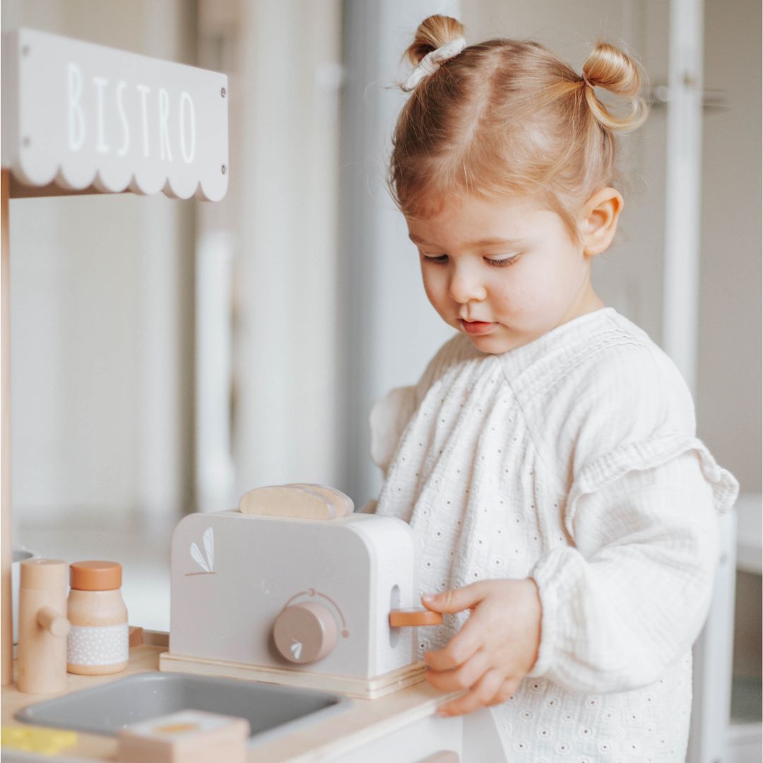 Een kind speelt met de label label houten speelgoed broodrooster en duwt de hendel naar beneden.
