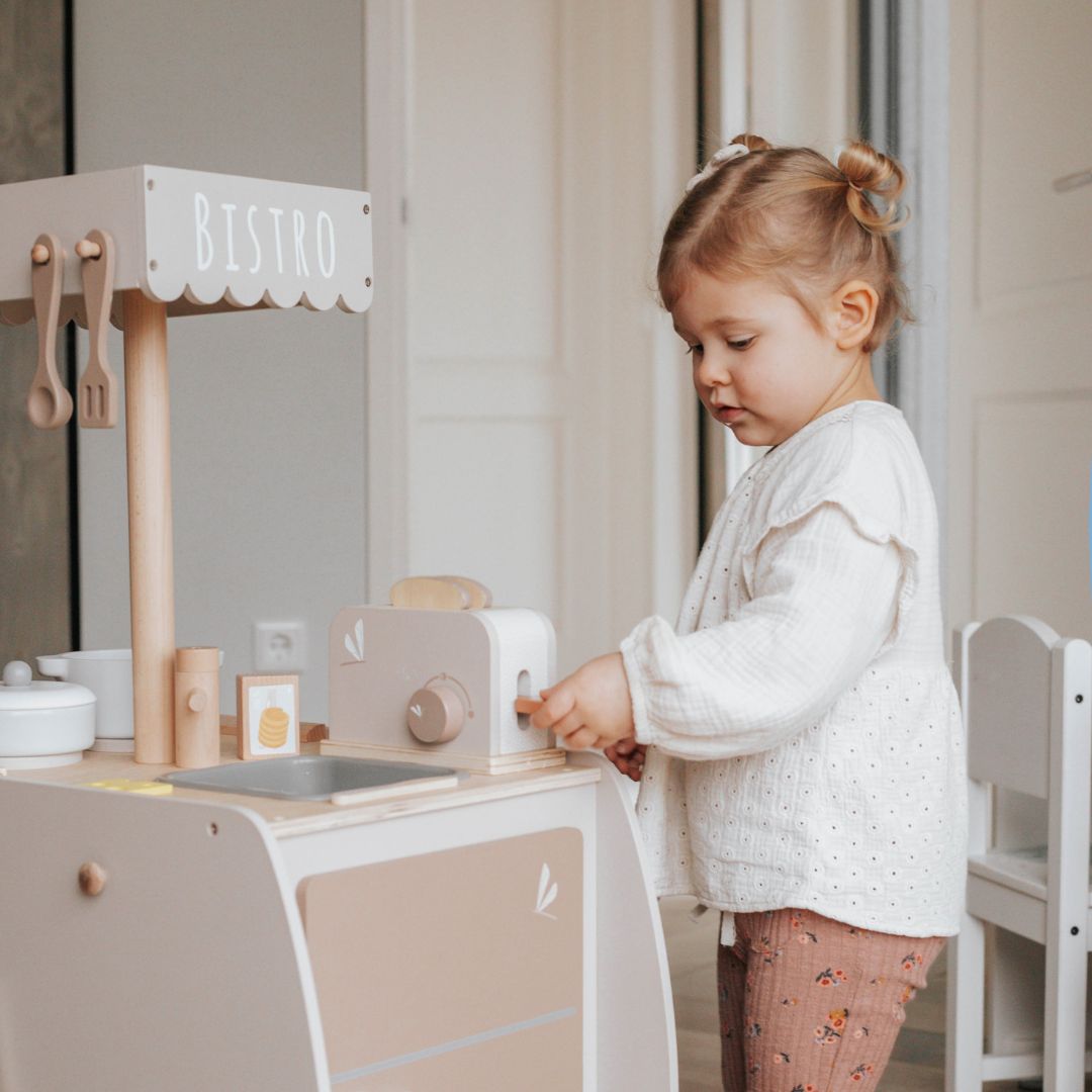 Een kind speelt met de label label houten speelgoed broodrooster in een speelgoedkeuken.