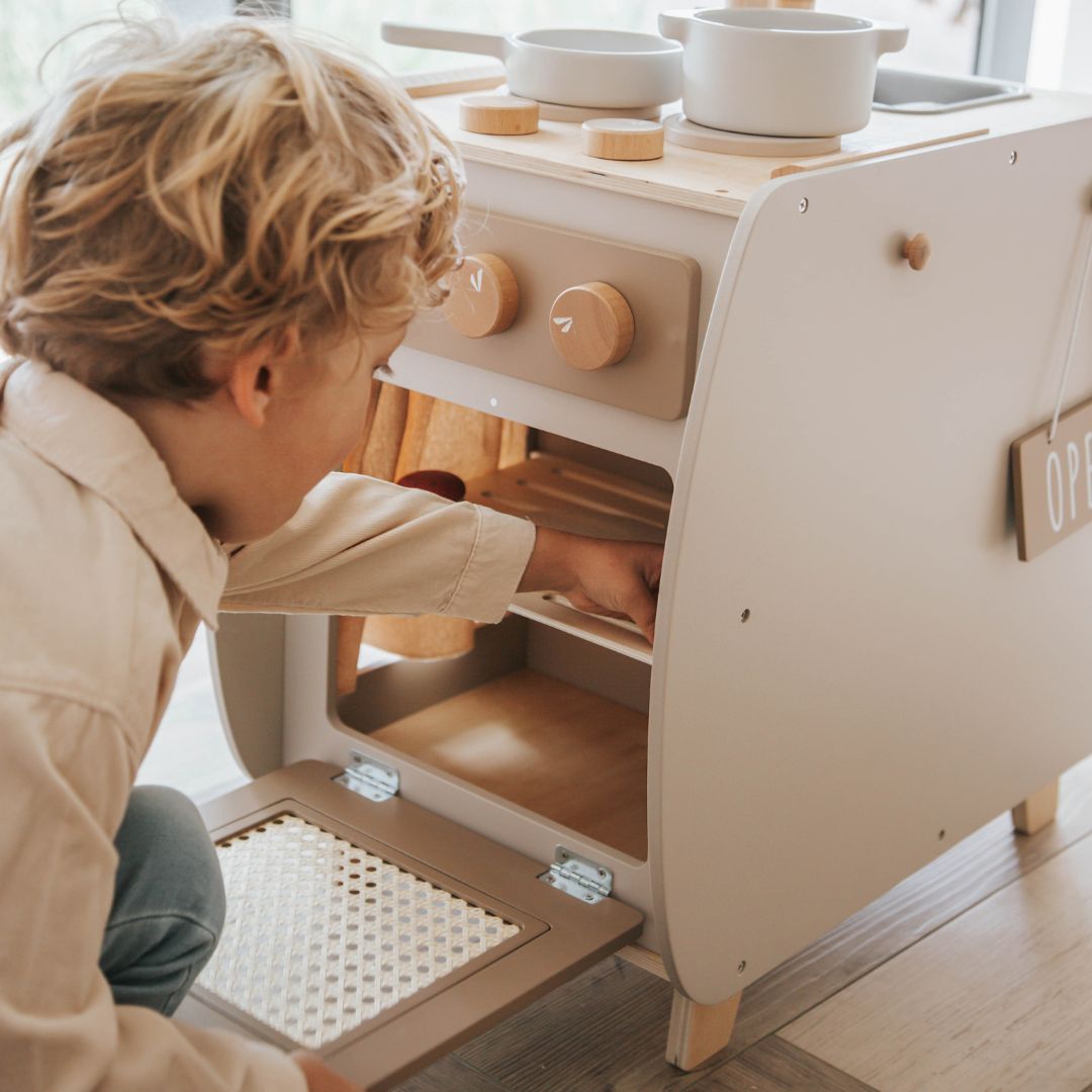 Een kind opent de oven van de Label Label houten kinderkeuken bistro.
