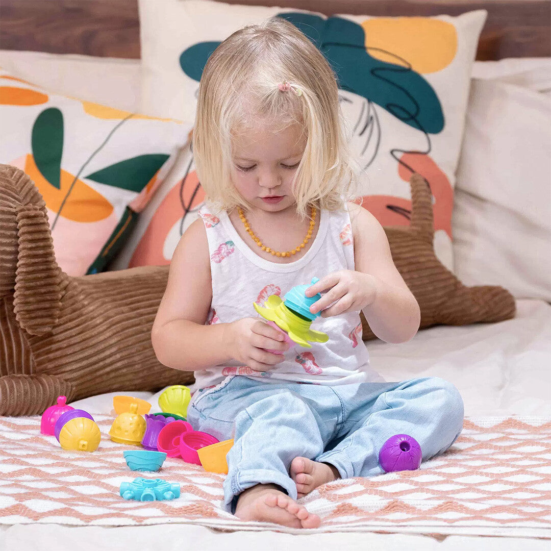 Een peuter zit op bed en speelt met de kleurrijke lalaboom educatieve klikkralen.