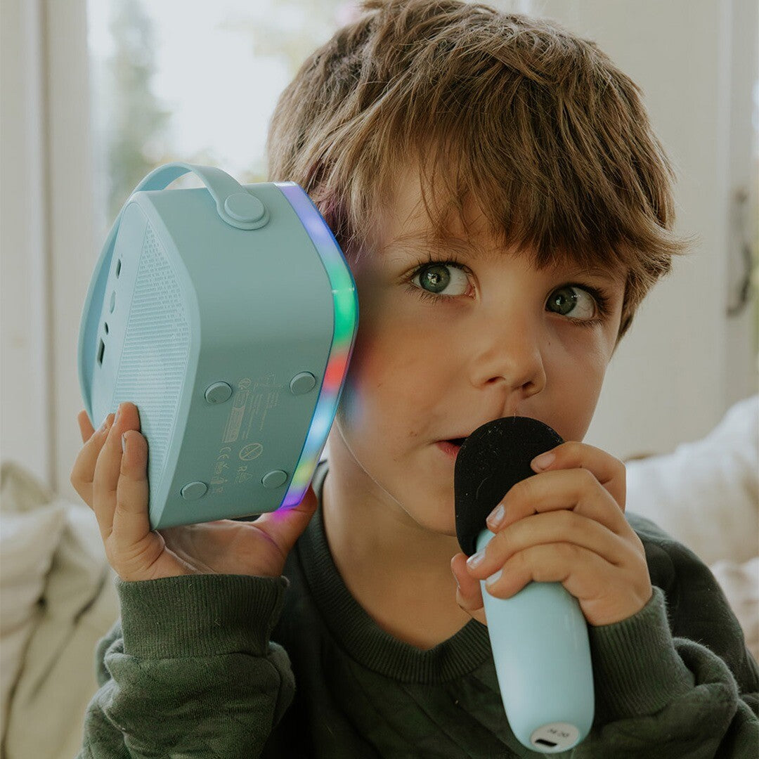Een jongen zingt in een lalarma copenhagen microfoon terwijl hij de lichtgevende karaokespeaker vasthoudt.