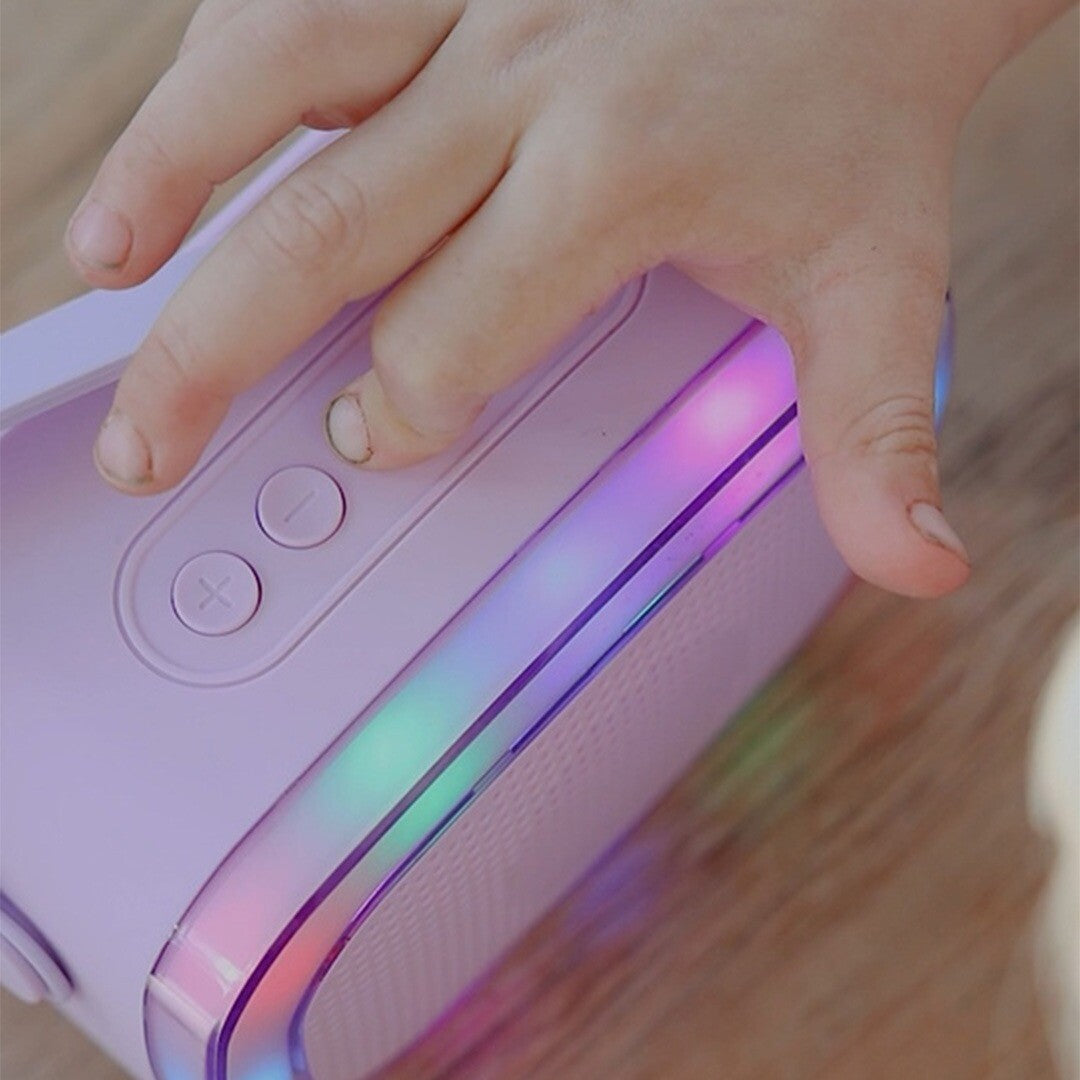 Een kinderhand drukt op een knop van de paarse lalarma copenhagen karaokeset speaker met kleurrijke verlichting.