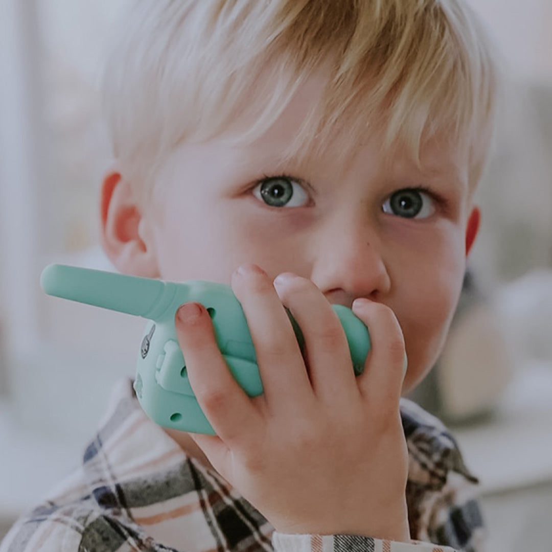 Jonge jongen met blond haar houdt een lalarma copenhagen walkie talkie in mintgroen tegen zijn oor.
