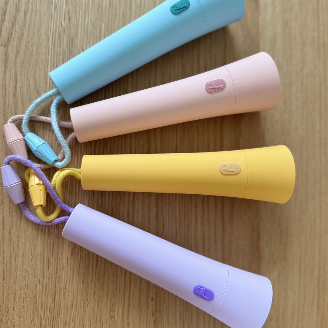 Vier lalarma copenhagen zaklampen in pastelkleuren, liggend op een houten ondergrond, van bovenaf gezien.