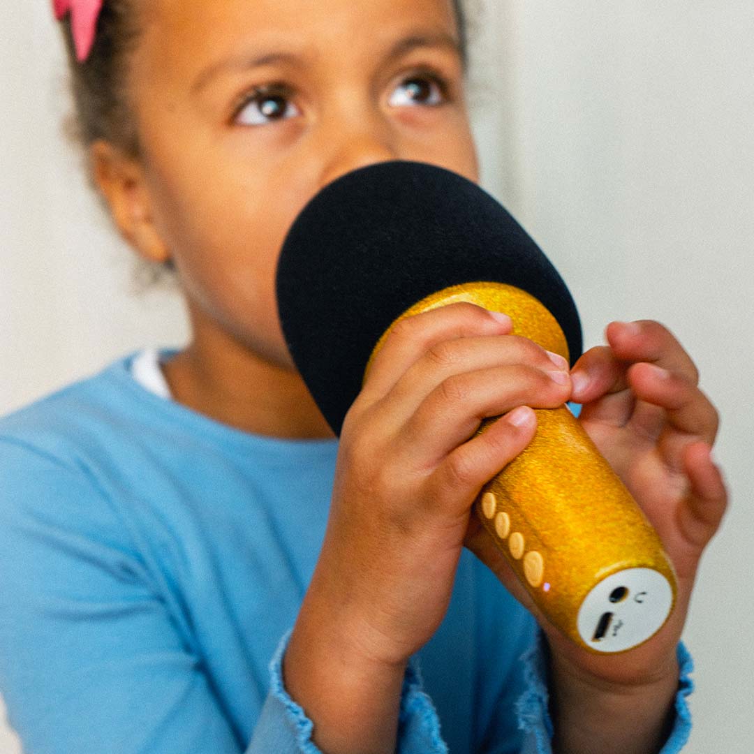 Een meisje houdt de gouden glitter karaoke microfoon vast, met zicht op de aansluitingen aan de onderkant.