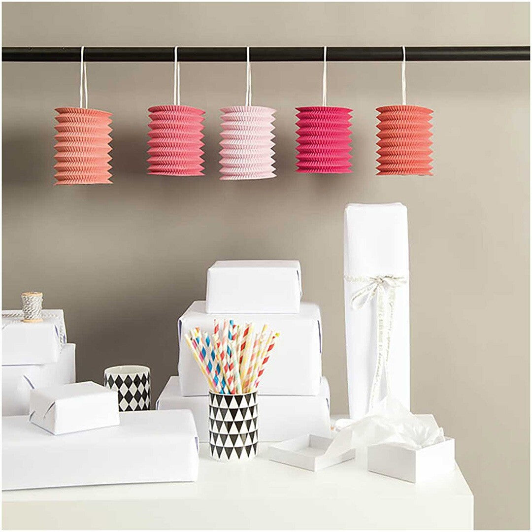 Vijf Rico Design papieren lampions in roze en oranje tinten hangen aan een stang.