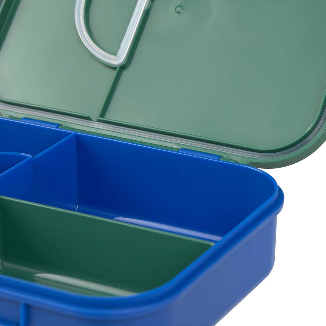 Close-up van de open Lässig bento-broodtrommel met blauwe en groene vakken en de groene deksel met siliconen rand.