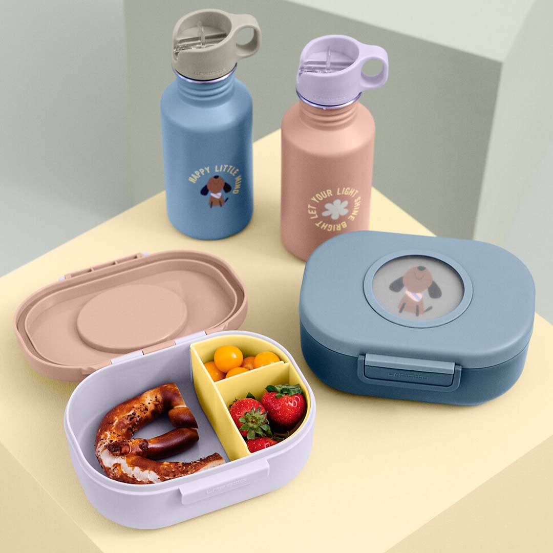 Een collectie Lässig kinderlunchartikelen met een open broodtrommel, een gesloten broodtrommel en twee bijpassende drinkflessen.